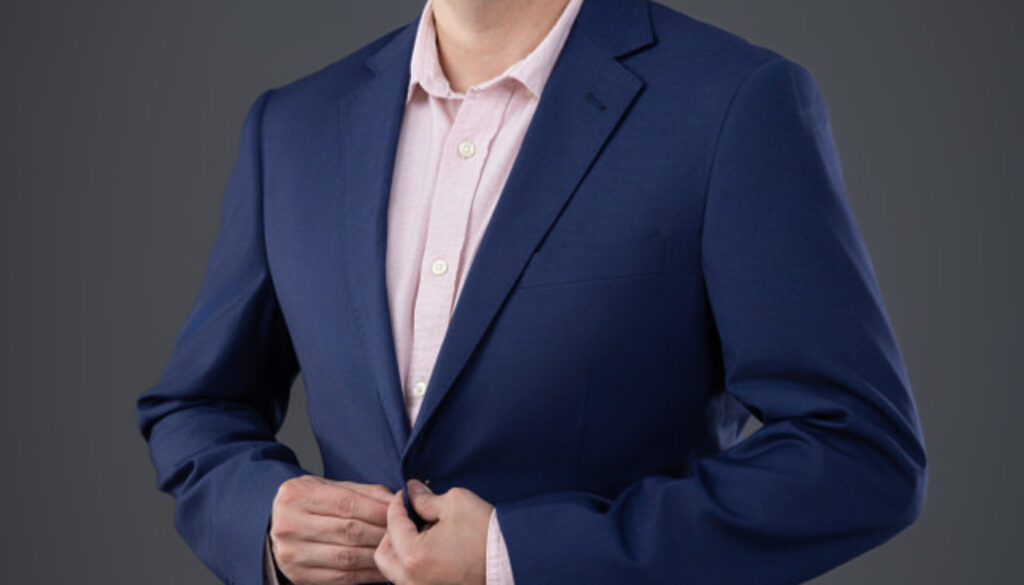 Hombre con blazer azul marino y camisa rosada en sesión profesional de marca personal