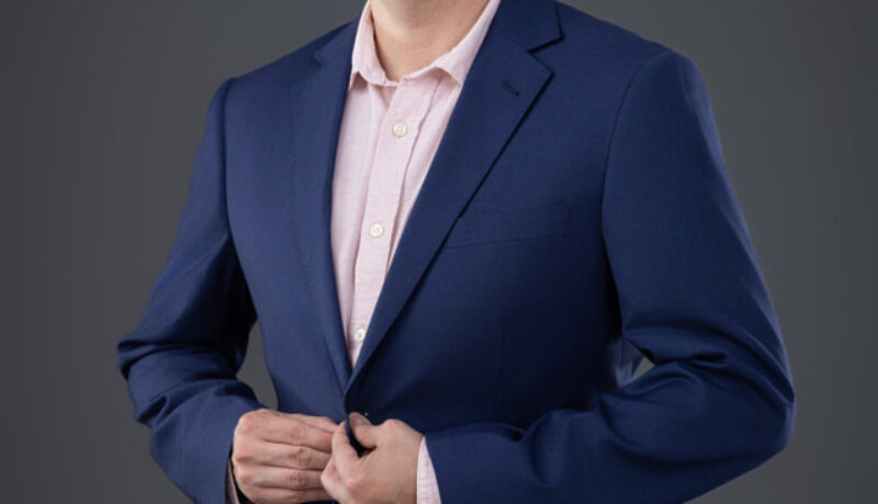 Hombre con blazer azul marino y camisa rosada en sesión profesional de marca personal